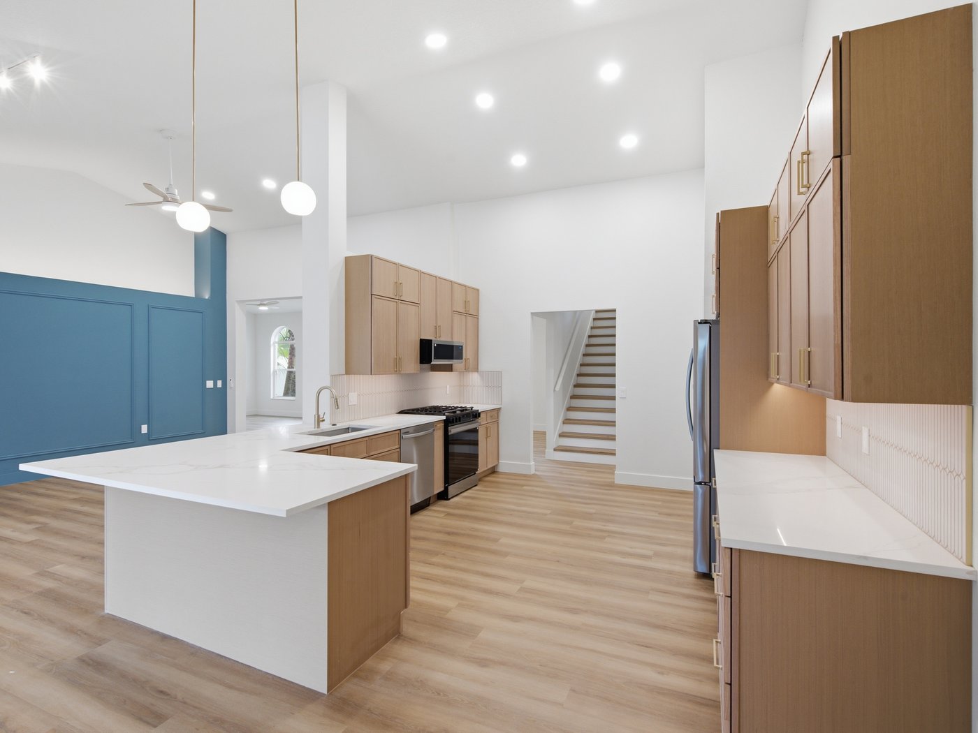 Light wood cabinets and a white quartz island under pendant lights, with a navy accent wall.